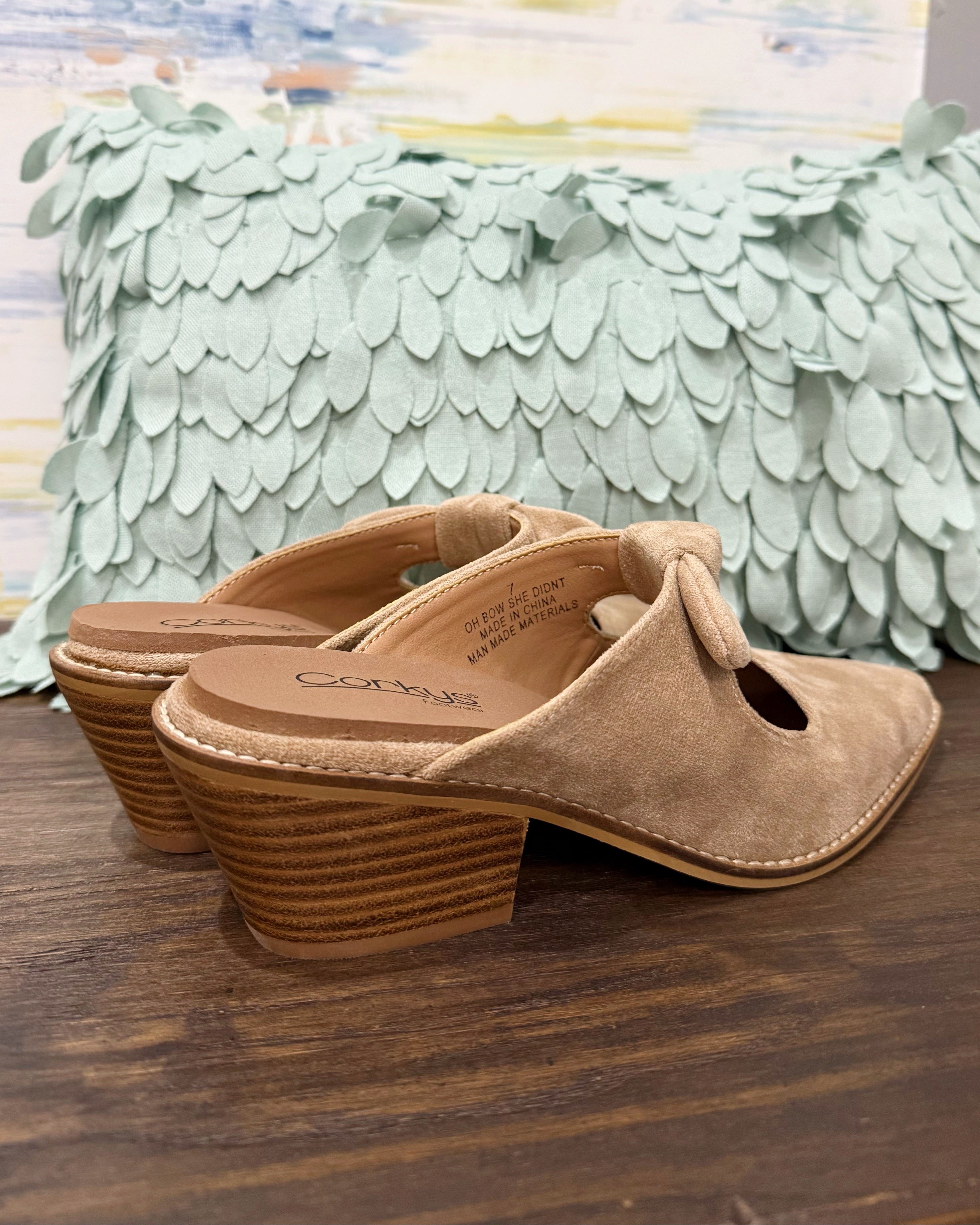 Corkys Oh Bow She Didn't Mule in camel faux suede is a chic slip-on shoe featuring a 2.5" wood grain block hell and a playful knotted bow detail