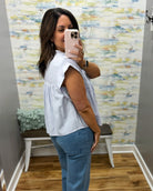 Woman taking a mirror selfie wearing a light blue top and jeans in a room with colorful wallpaper.