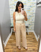 woman wearing stripe pants and taupe tank.