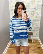 Woman wearing a blue and white striped sweater taking a mirror selfie.