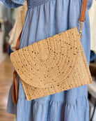 Woven handbag held by a person wearing a blue dress