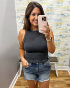 woman wearing black tank with denim shorts.