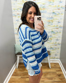 Woman wearing a blue and white striped sweater taking a mirror selfie.