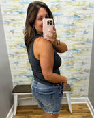 woman wearing black tank with denim shorts.