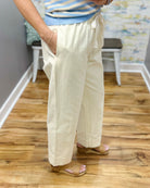 Person wearing light-colored pants and a striped shirt on a wooden floor.