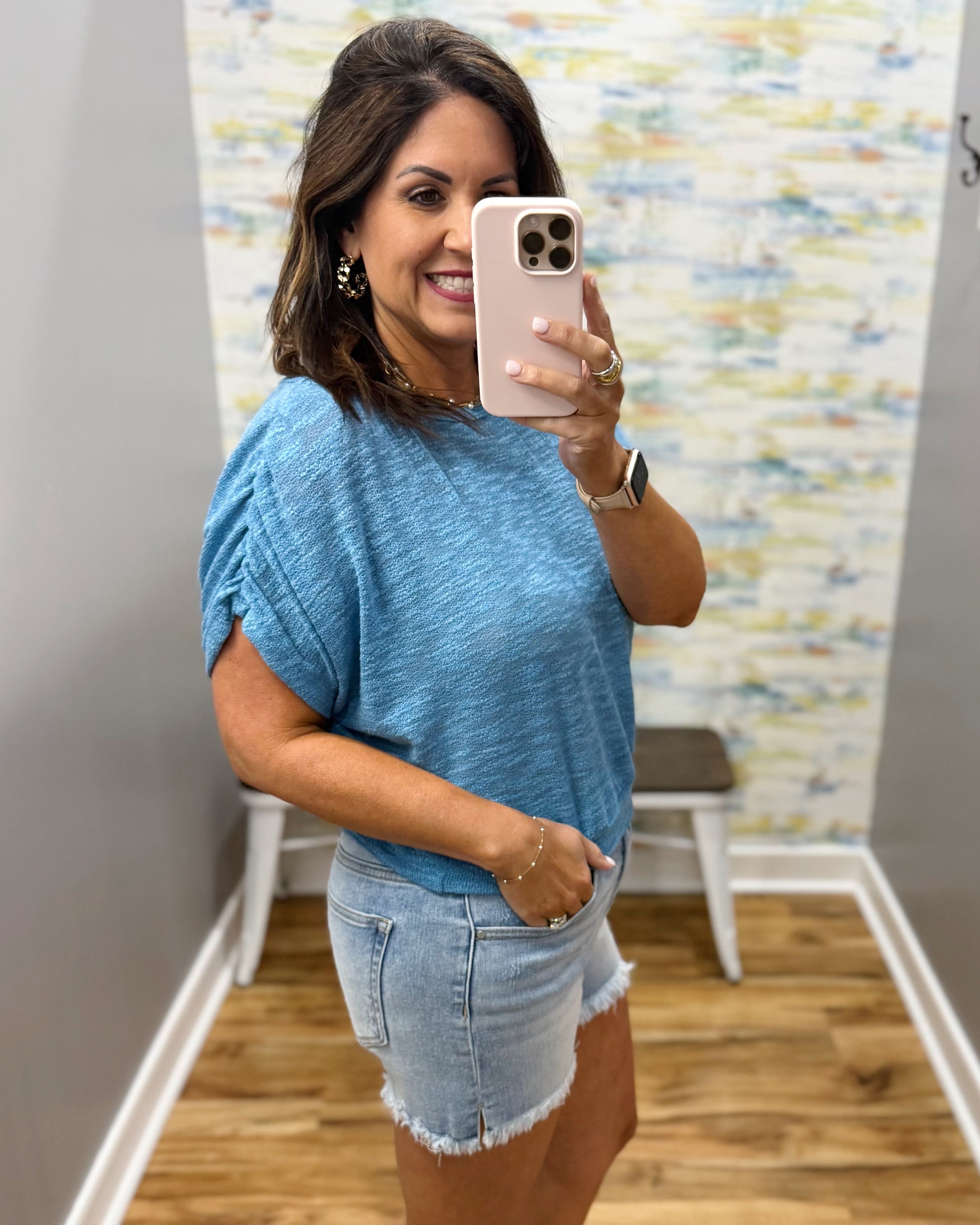woman wearing a blue top with denim shorts.