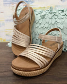 Beige sandals with woven sole on a wooden surface with decorative background