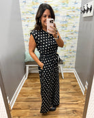 woman taking a selfie wearing a black and white polka dot jumpsuit.
