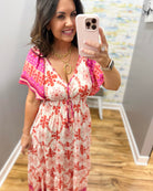 Woman taking a mirror selfie wearing a floral dress indoors.