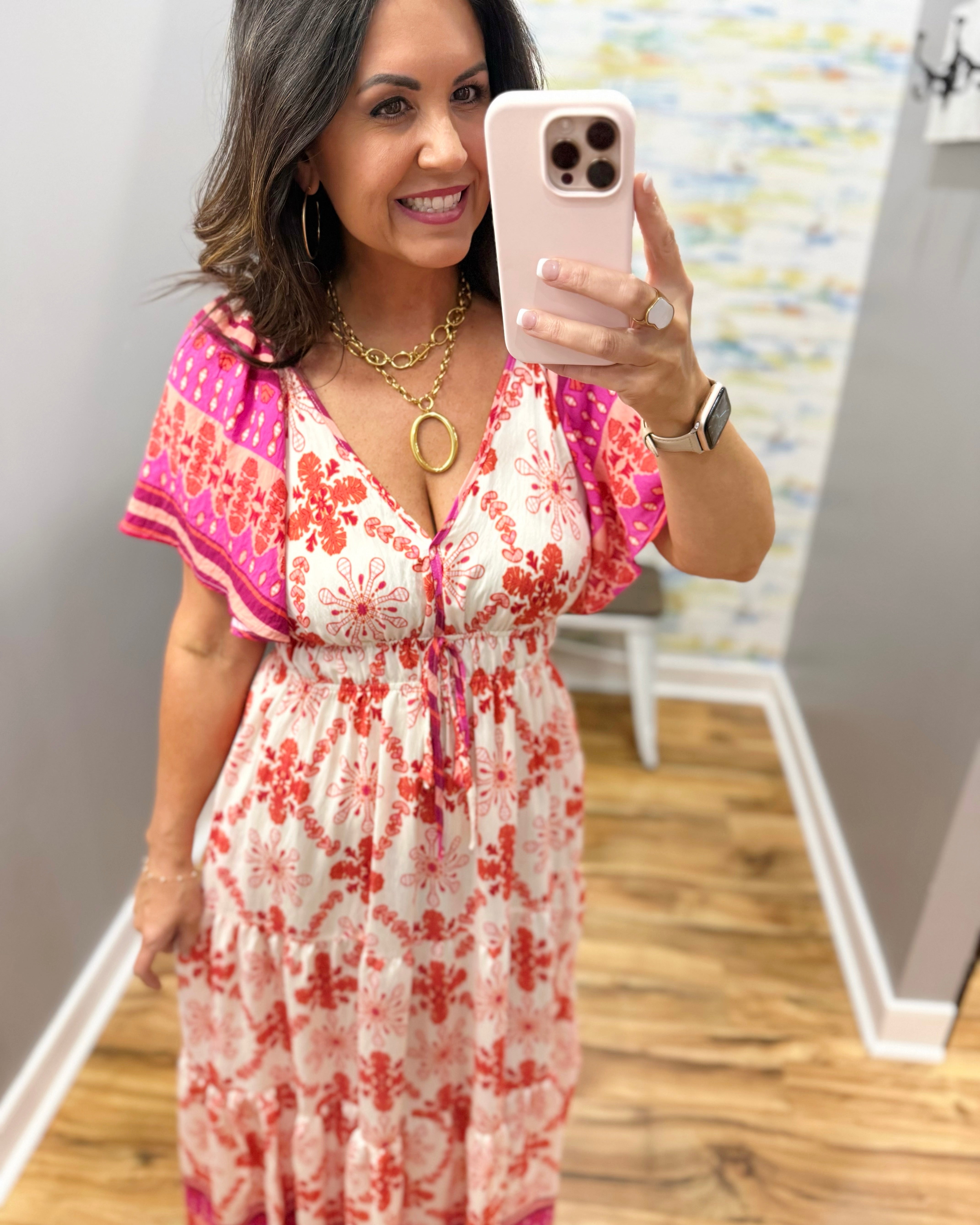 Woman taking a mirror selfie wearing a floral dress indoors.