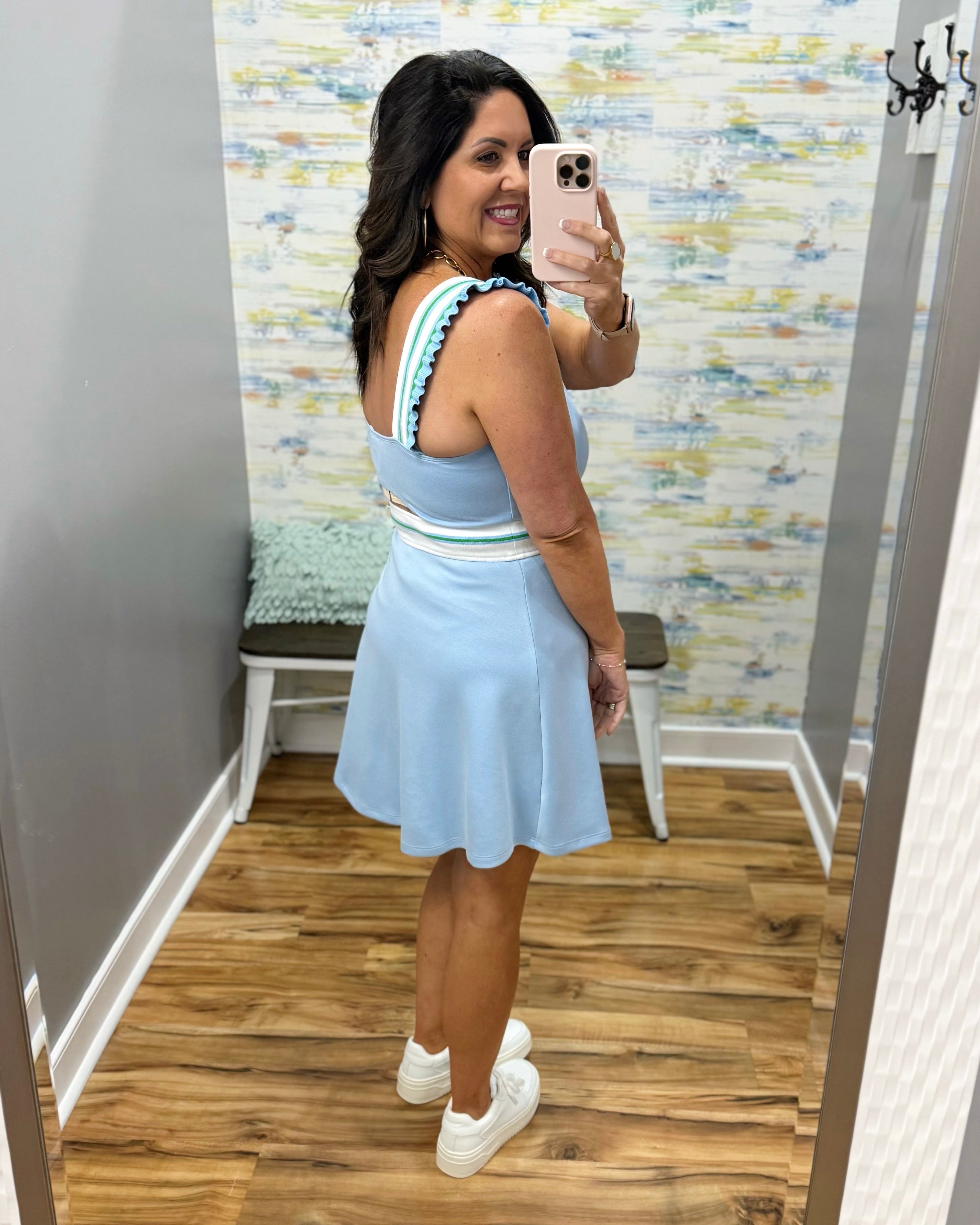 Woman taking a mirror selfie wearing a light blue dress with a striped top.