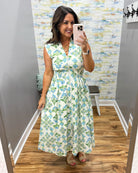 Woman taking a mirror selfie wearing a floral dress in a room with a colorful wall.