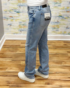 Person wearing light blue jeans with a visible brand label on a wooden floor.