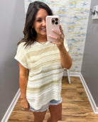 Woman taking a mirror selfie wearing a striped dress in a room with a patterned wall.