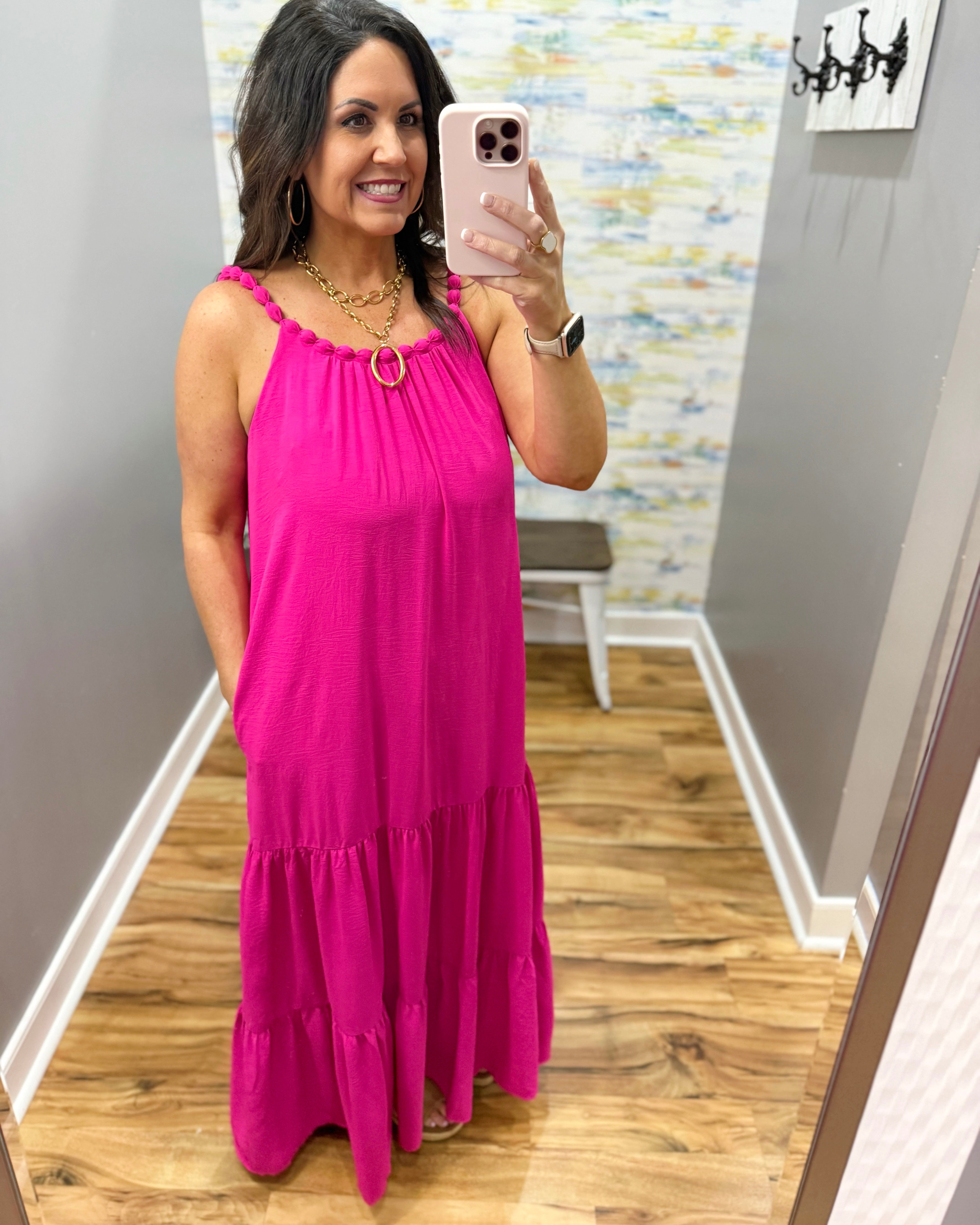 Woman wearing a pink dress in a room with a colorful wall.