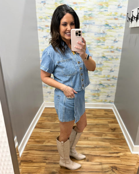 Woman wearing a denim skort and denim top with beige boots.