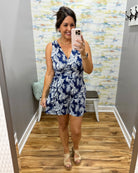 Woman taking a mirror selfie wearing a blue floral dress in a fitting room.