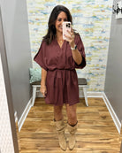 woman taking a selfie wearing a burgundy wrap dress featuring a V-neckline, cinched waist, and flowy short sleeves for a feminine silhouette.