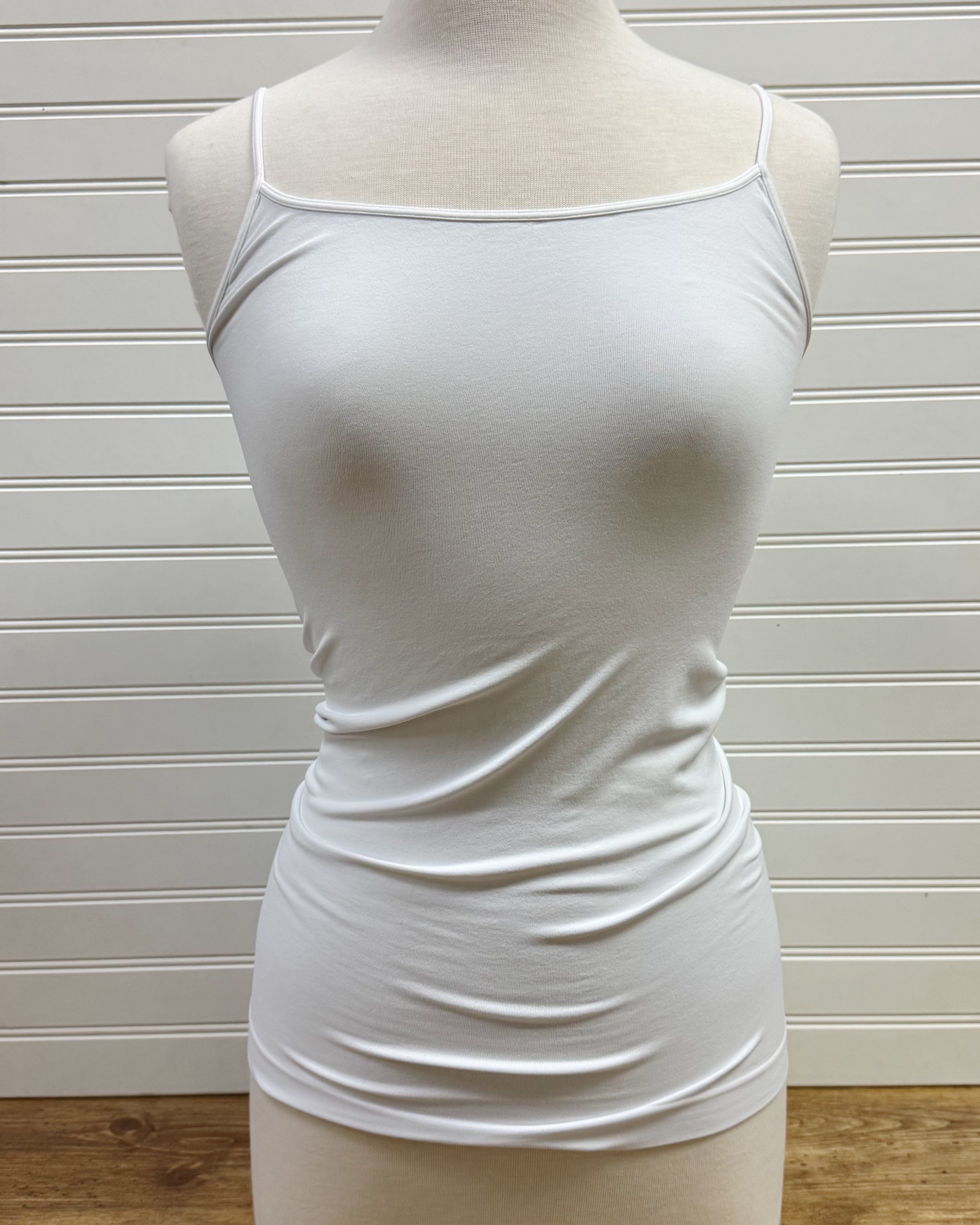 A white, sleeveless, scoop neck tank top displayed on a mannequin against a plain background.