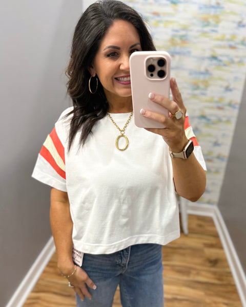 woman wearing white tee with colorful sleeves and chunky gold necklace
