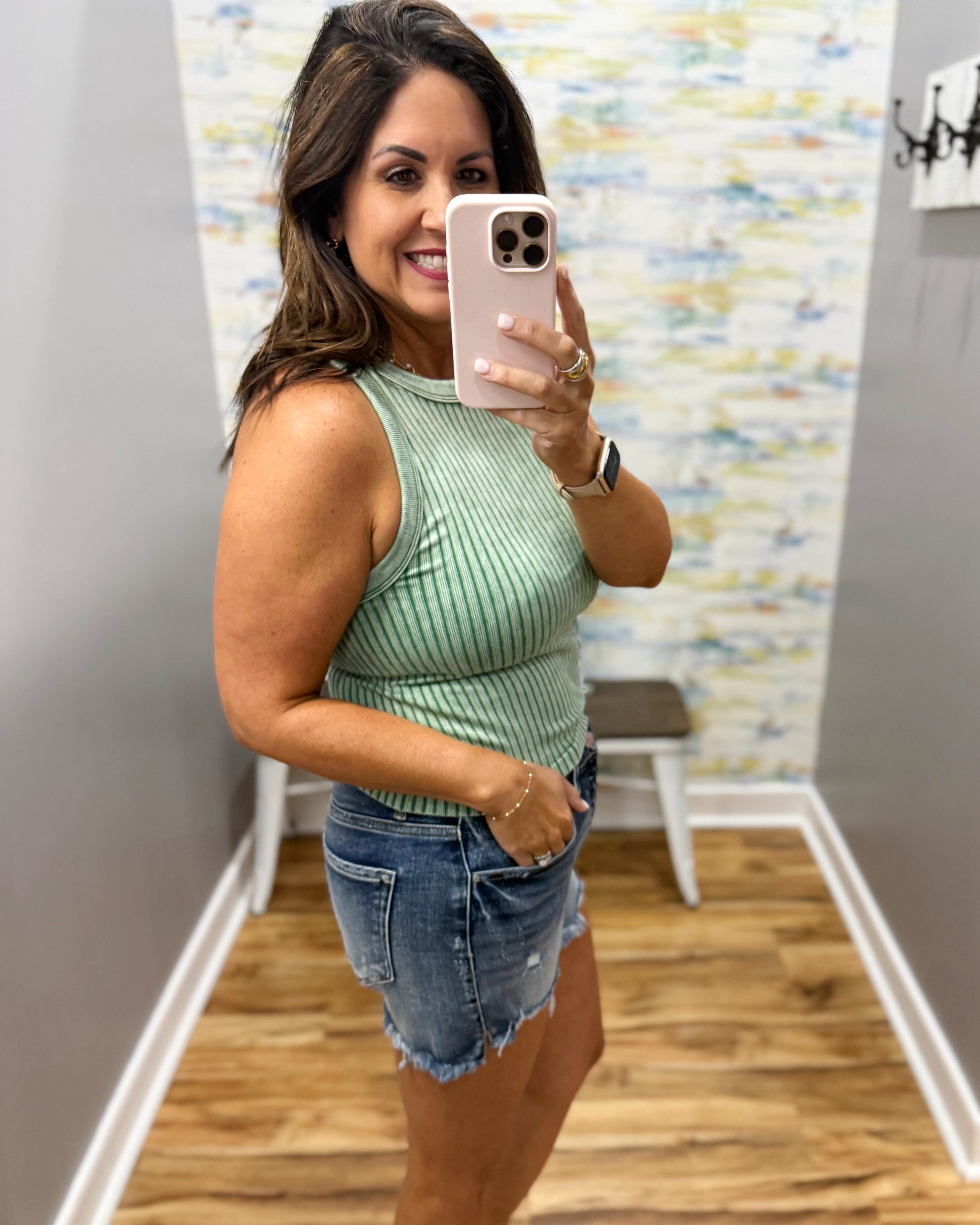 woman wearing dark green tank with denim shorts.