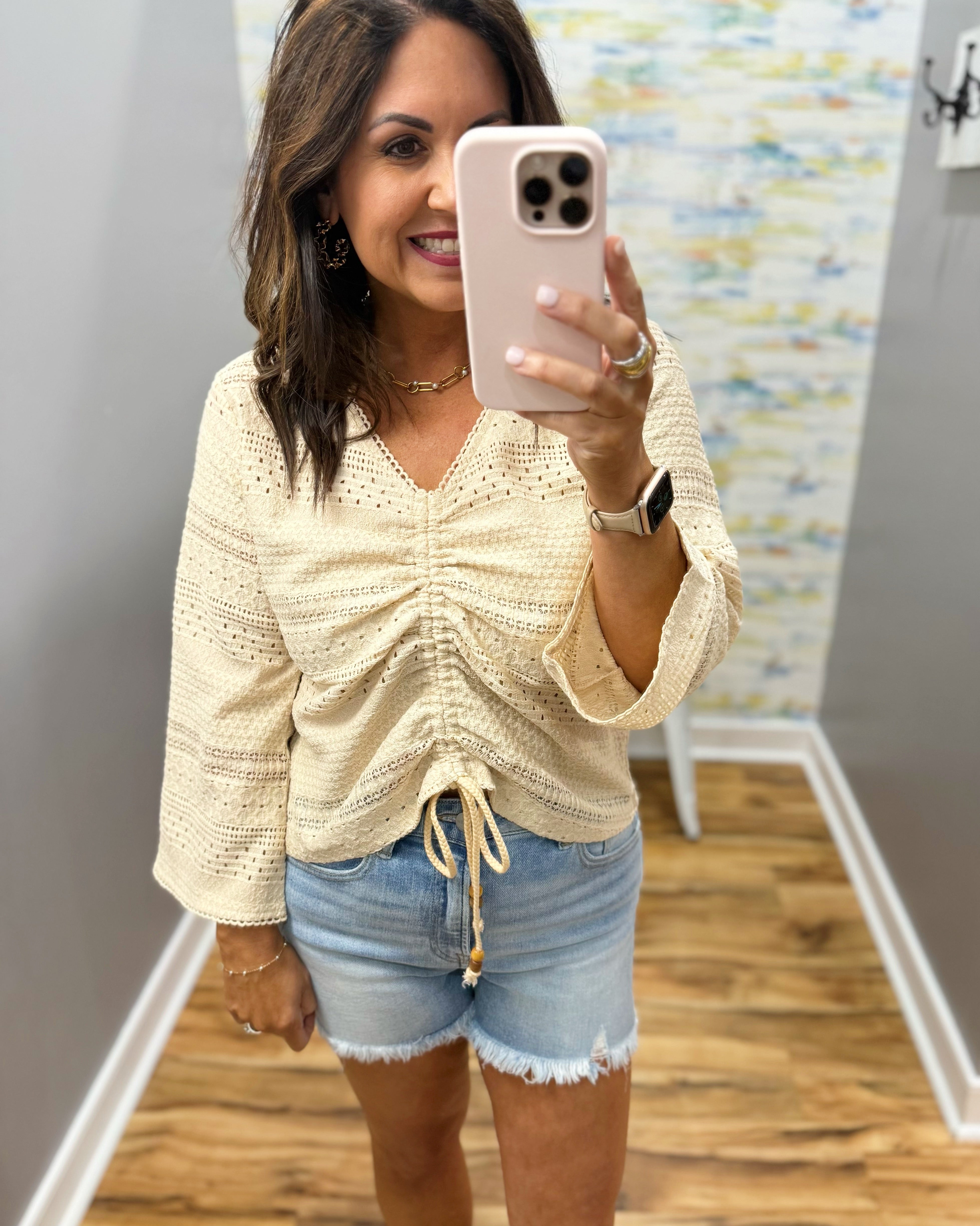 woman wearing a bell sleeve top in natural. 