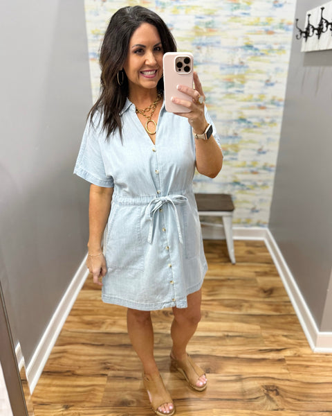 Woman wearing a light blue dress in a room with a patterned wall.