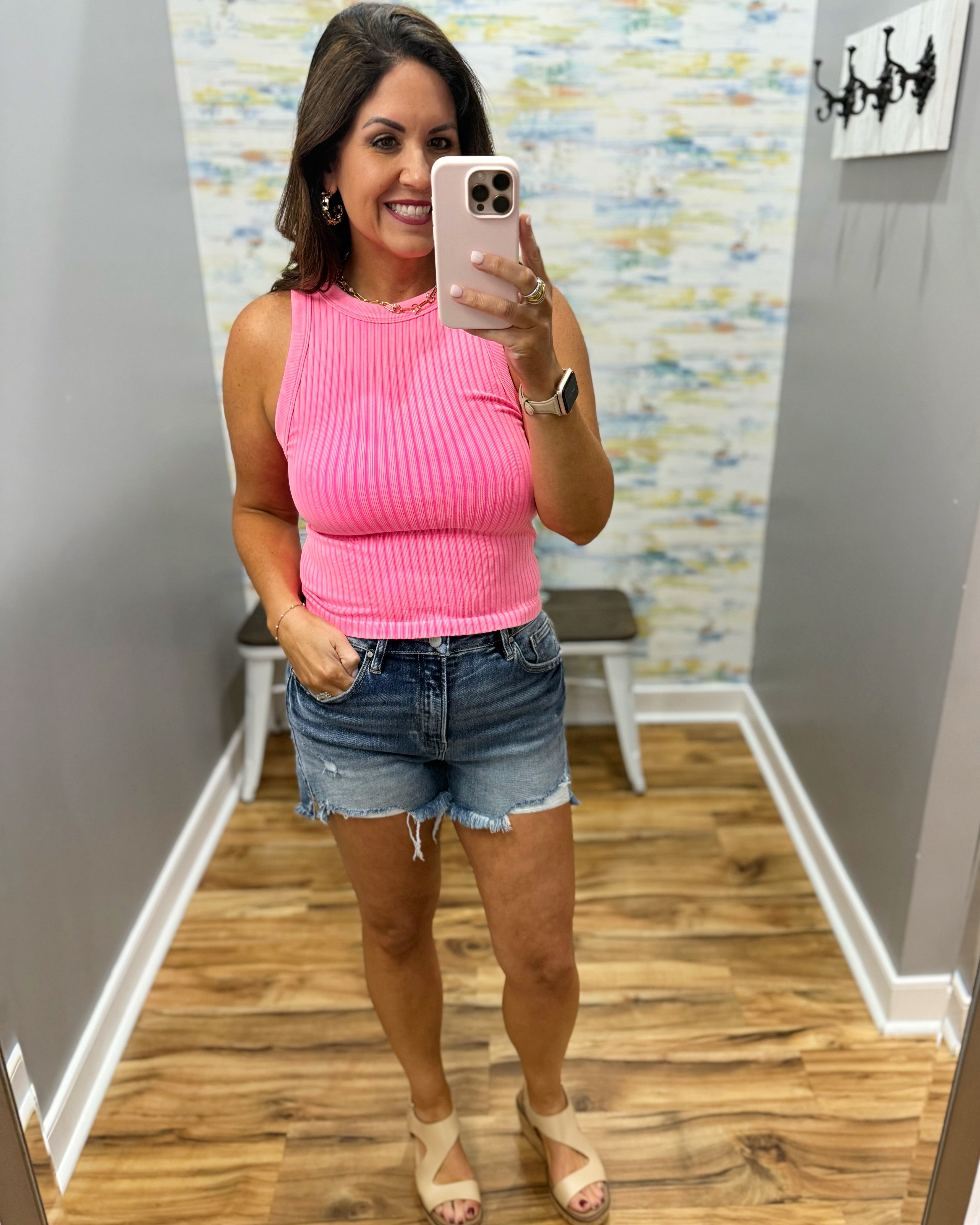 woman wearing neon coral tank with denim shorts.