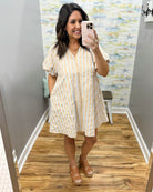 Woman taking a mirror selfie wearing a natural and white striped dress.