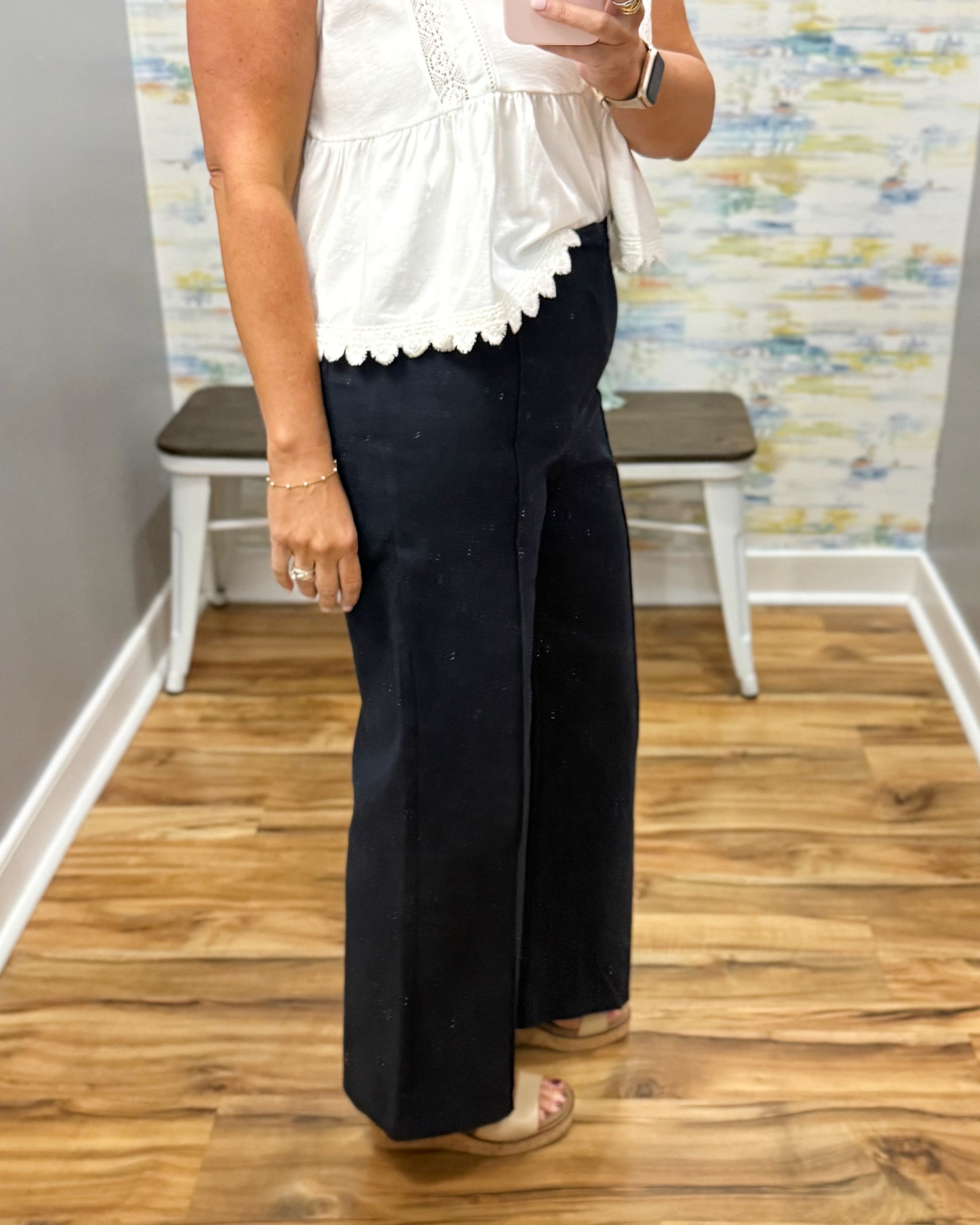 woman wearing navy pants with white top.