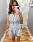 Woman taking a mirror selfie wearing a black and white striped romper.
