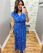 Woman taking a mirror selfie wearing a blue dress with a white pattern.