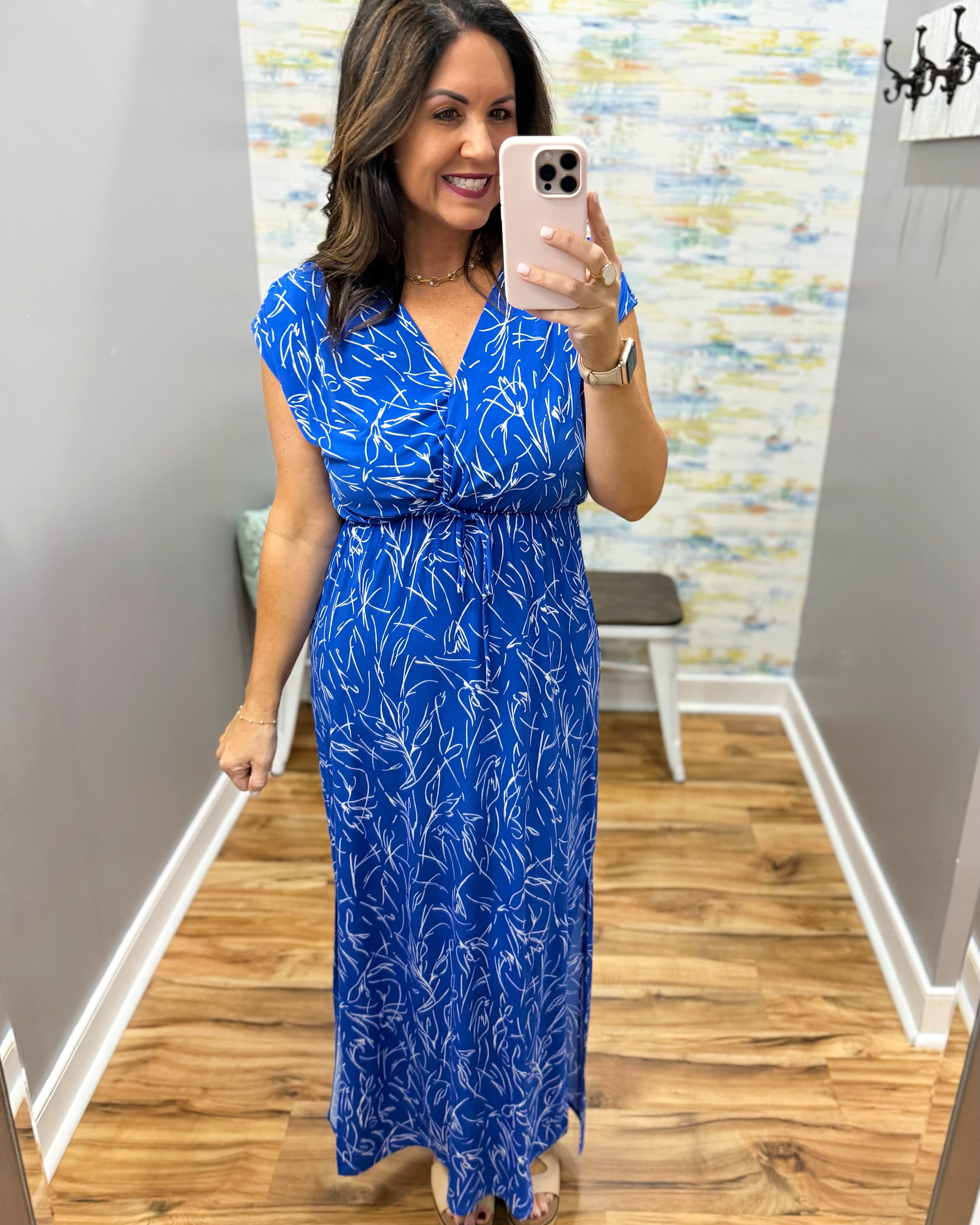 Woman taking a mirror selfie wearing a blue dress with a white pattern.