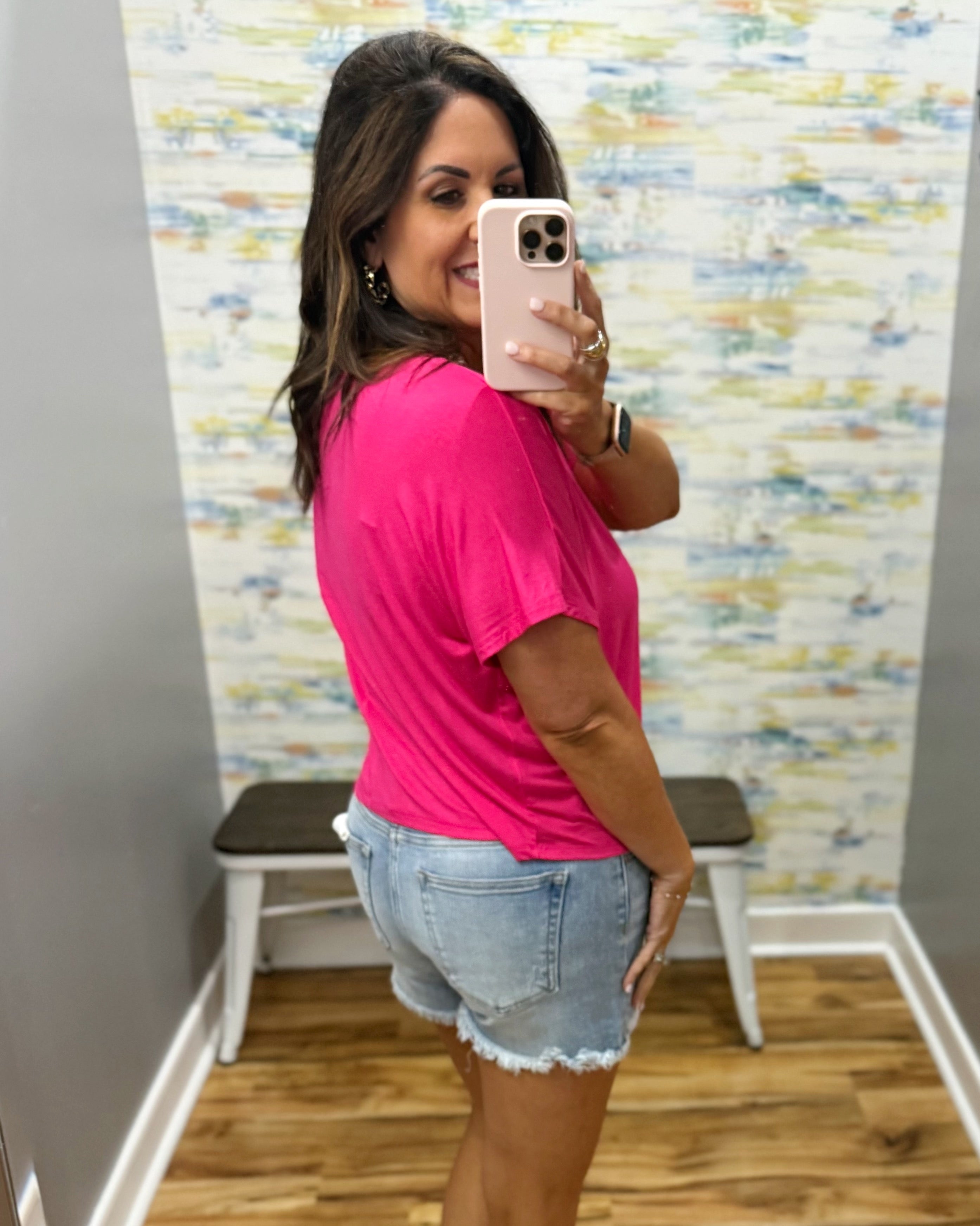 woman wearing hot pink tee with denim shorts.