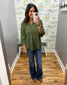 woman wearing a olive 3/4 sleeve flowy top with Judy Blue flare jeans and Corkys Pity Party wedge shoes in cognac.