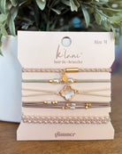 Set of hair ties and bracelets on a 'kilani' branded card with greenery in the background.