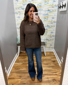 woman taking a selfie wearing a brown crochet knit sweater with Judy Blue dark wash flare jeans and Corky's Pity Party Wedge Shoes in cognac.