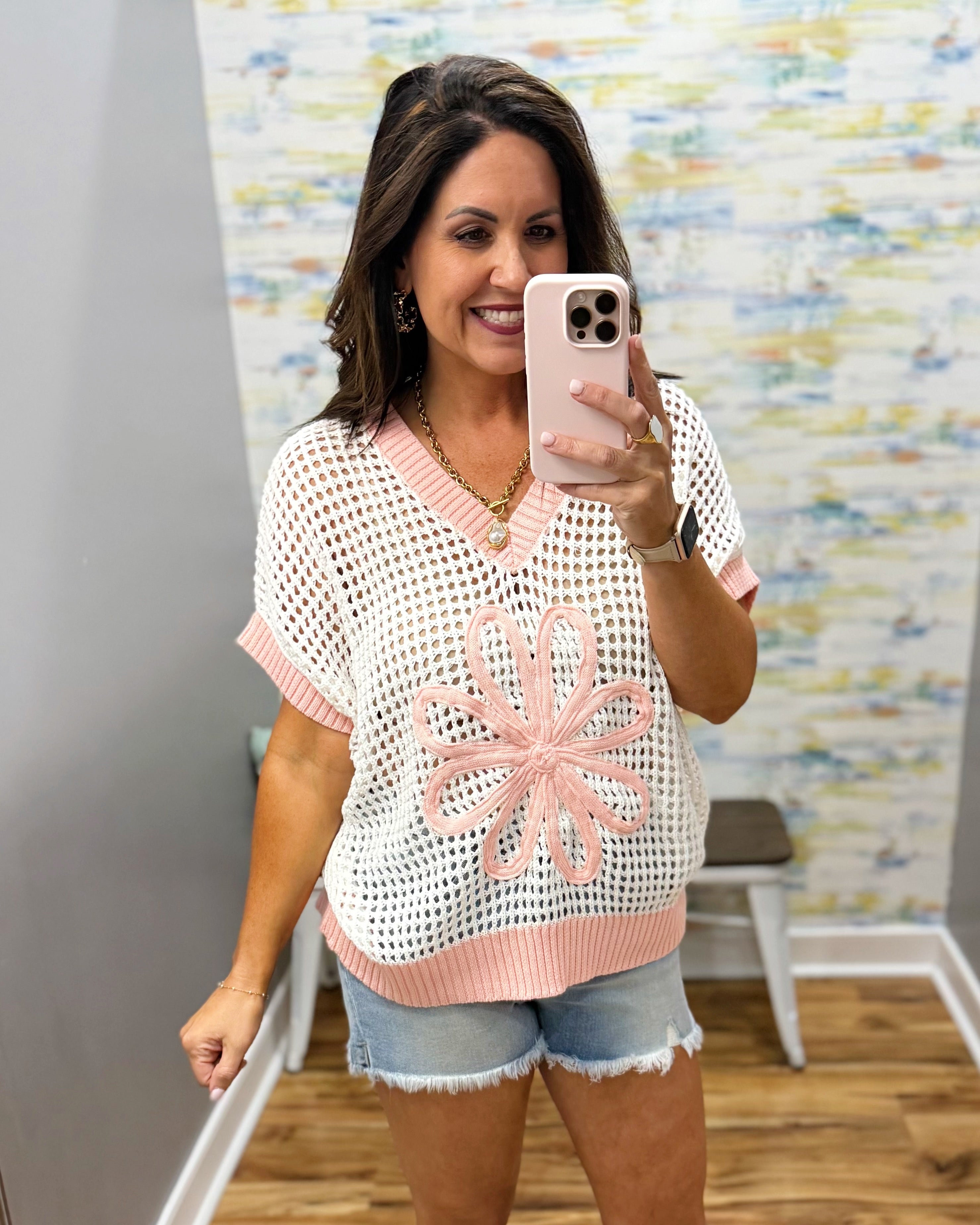 woman wearing a cream sweater with pink floral print.