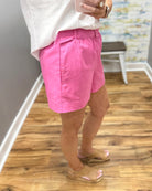 Person wearing pink shorts and a white top on a wooden floor.
