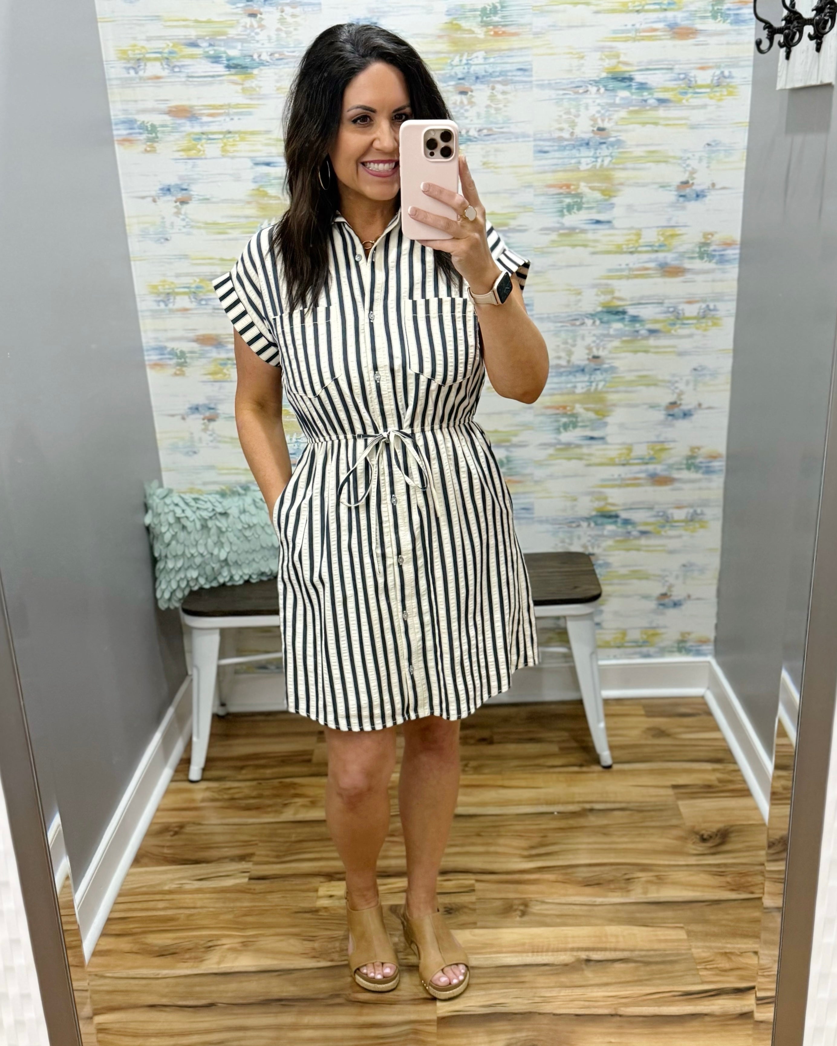 Woman wearing a black and white striped dress in a fitting room.