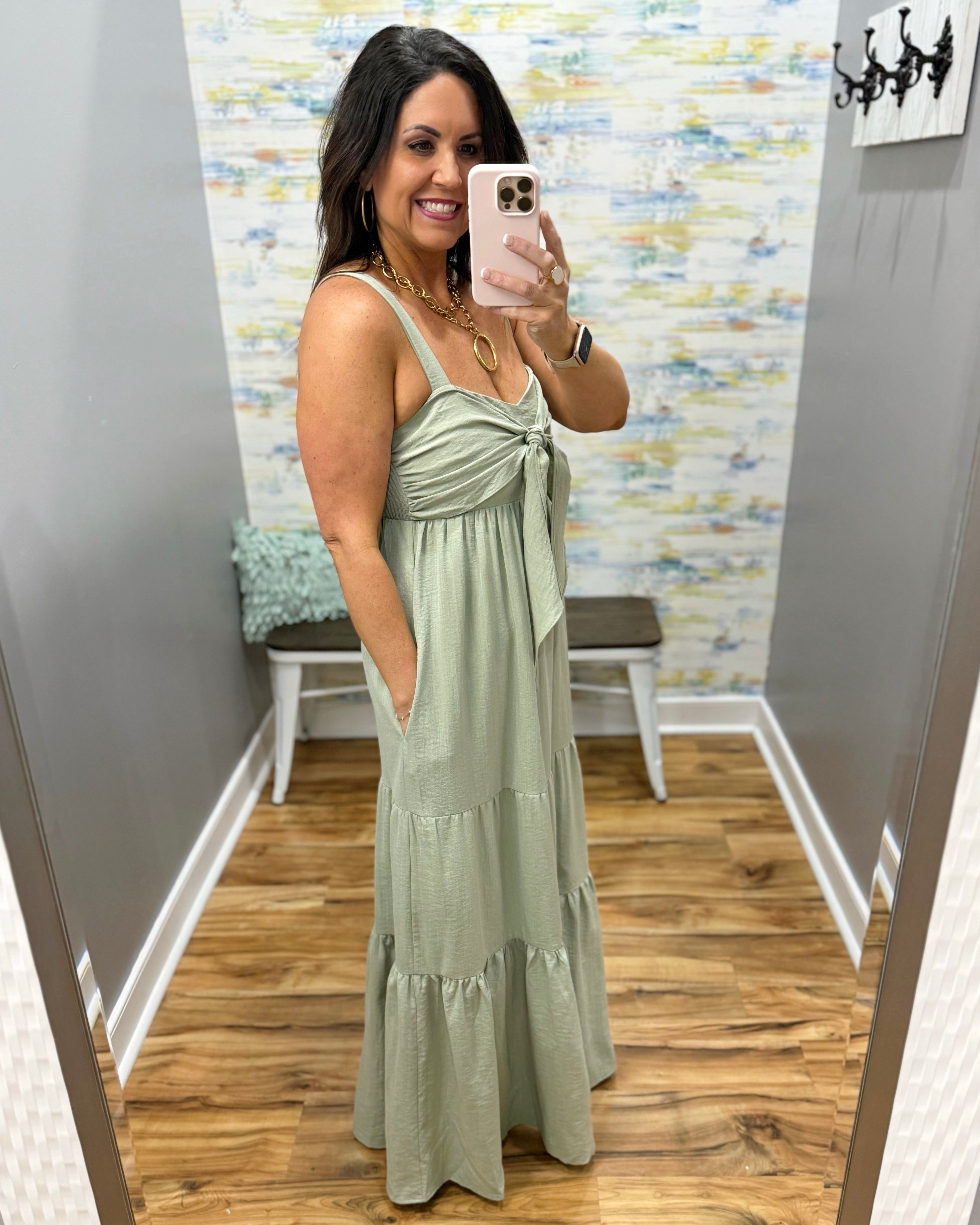 Woman wearing a light green dress in a room with a patterned wall.