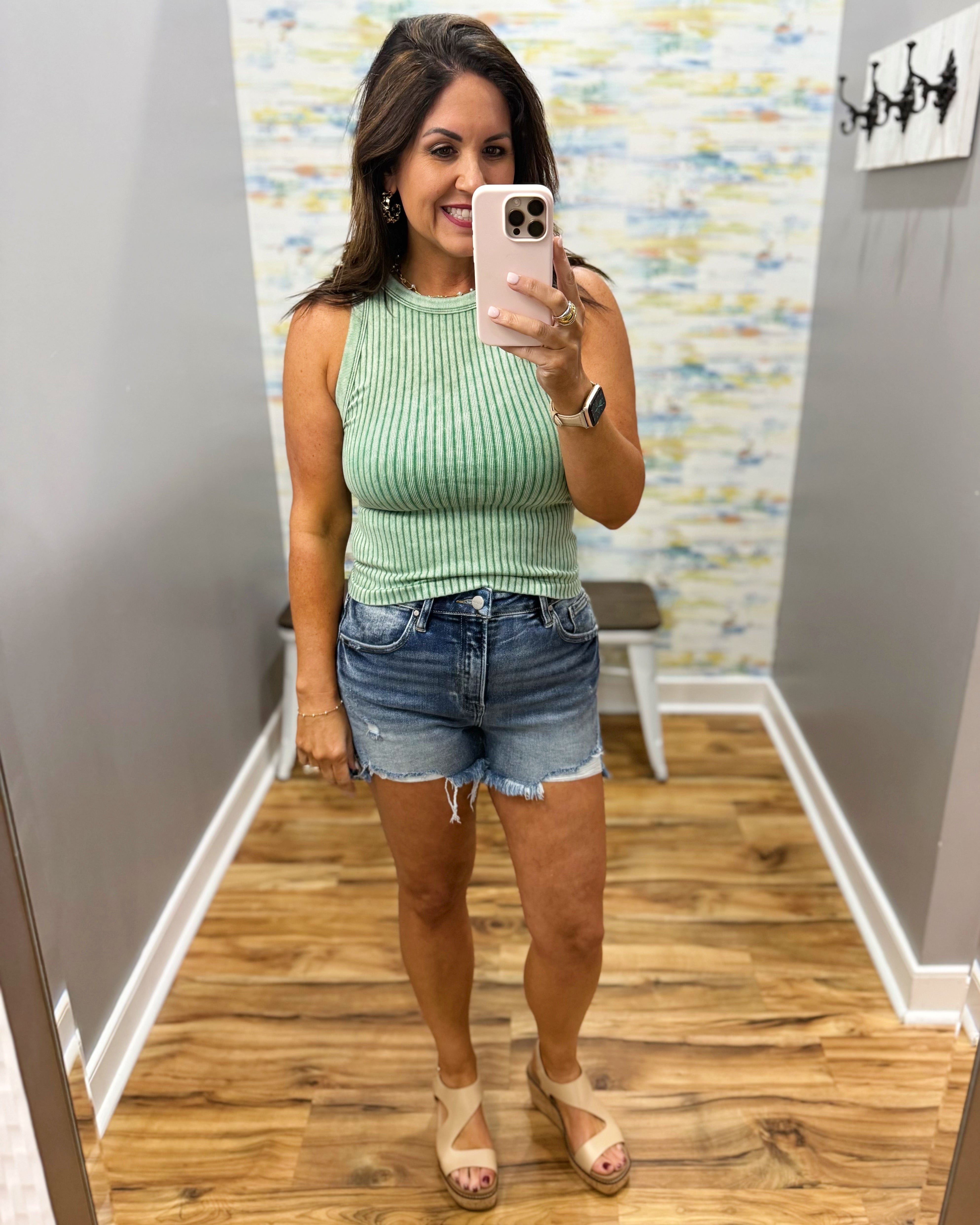 woman wearing dark green tank with denim shorts.