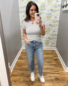 woman wearing stripe black and white tee, boyfriend style jeans and white sneakers.