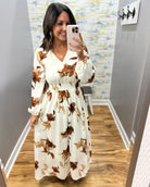 woman wearing a cream maxi dress with brown, black and taupe floral pattern. 