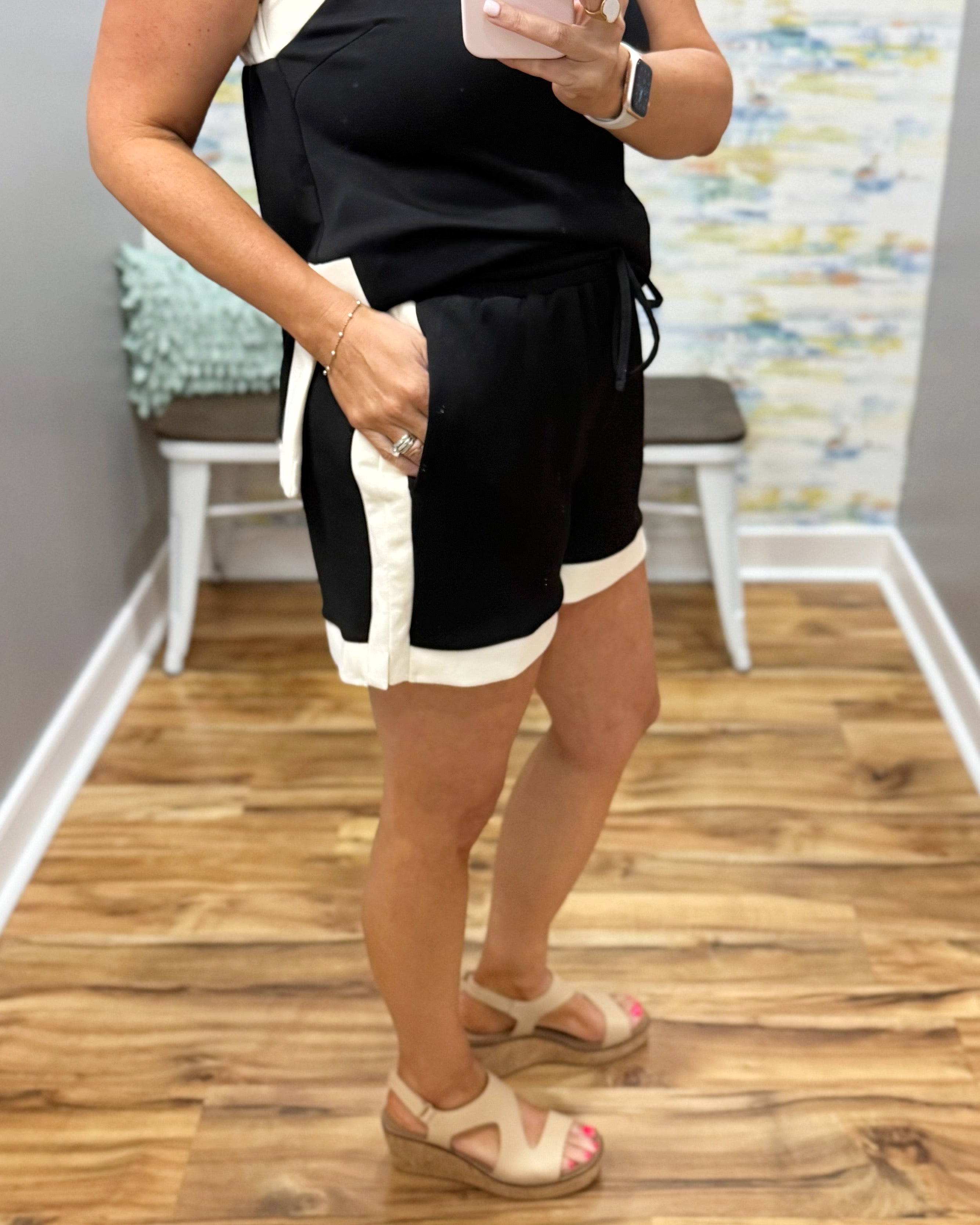 Person wearing black and white shorts with a colorful wall and wooden floor in the background