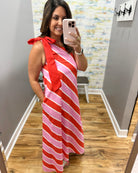 Woman taking a mirror selfie wearing a red and pink striped dress.