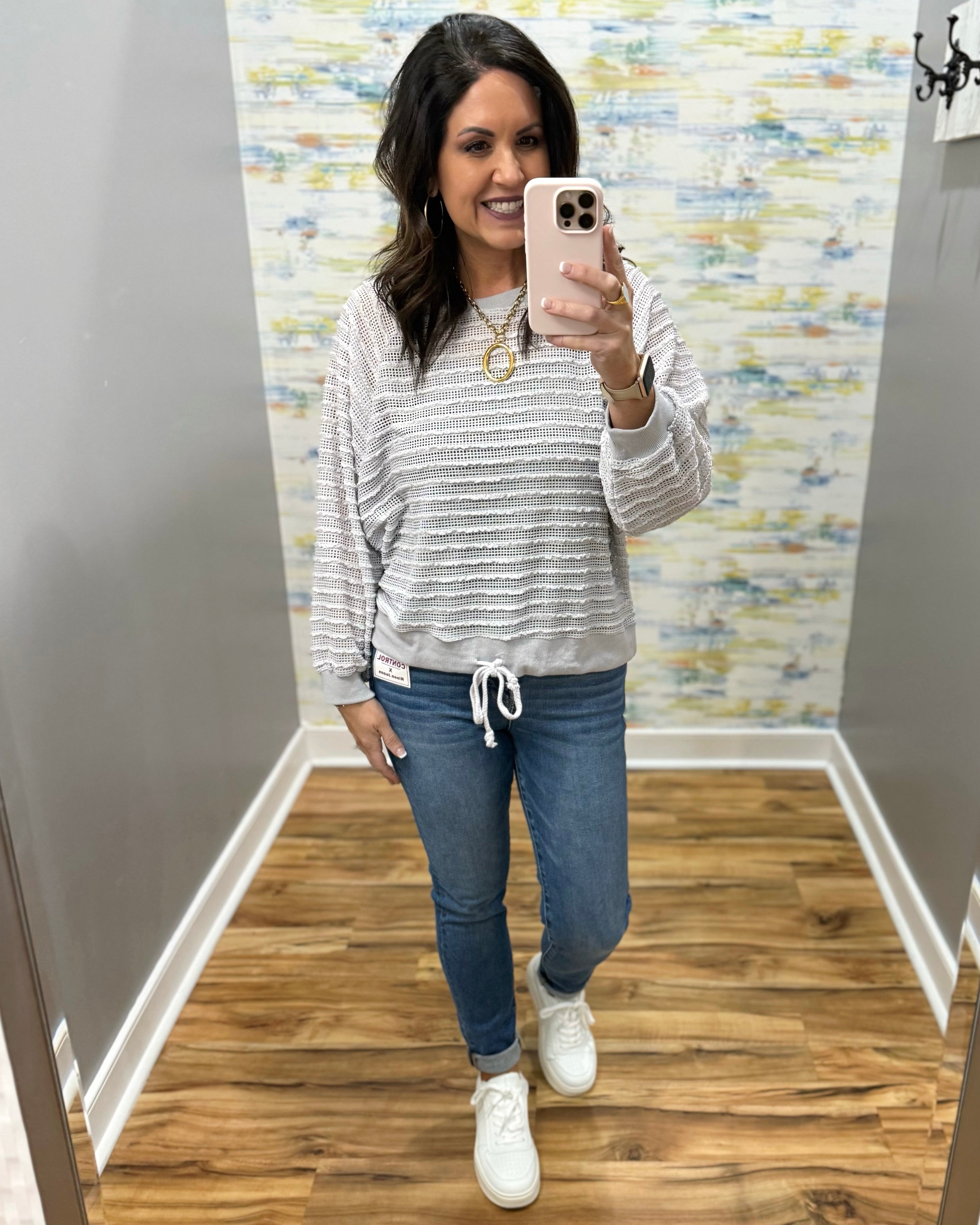 woman wearing a lightweight sweater top in stone color with skinny jeans and white sneakers.
