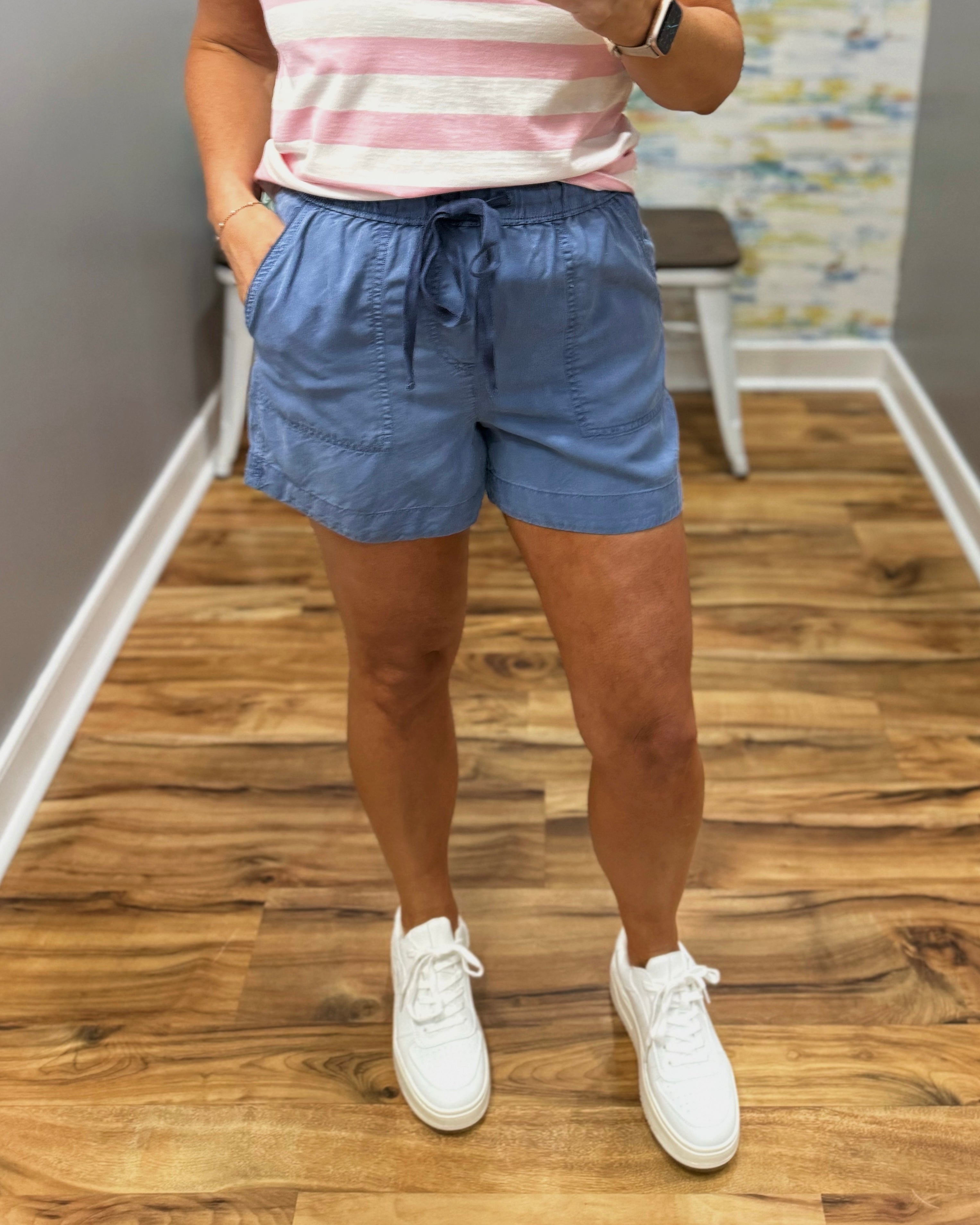 Person wearing blue shorts and a striped shirt on a wooden floor.
