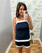 Woman taking a mirror selfie wearing a navy and white outfit in a room with a colorful wall.