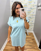 Woman taking a mirror selfie wearing a light blue dress in a room with a colorful wall.